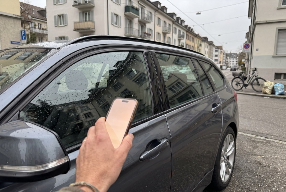 A hand opening a DRAIV car with a phone at the driver door